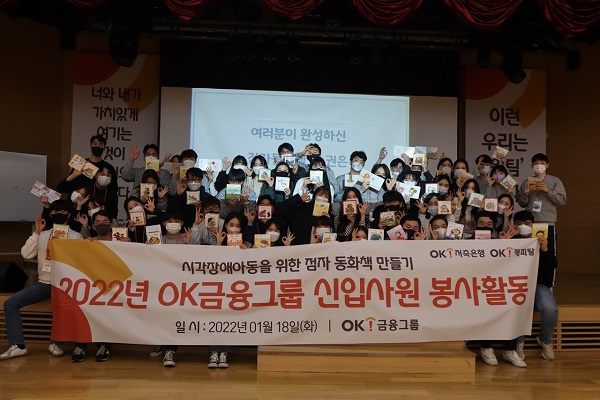 ▲OK금융그룹(회장 최윤)은 지난 18일 자사 신입사원을 대상으로 ‘점자 동화책 만들기’ 봉사활동을 펼쳤다. 사진은 완성된 점자 동화책을 들고 포즈를 취한 신입사원 단체 사진.