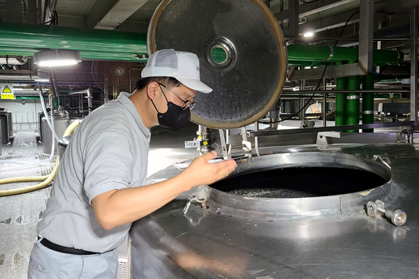 ▲허준원 생산본부 품질보증팀 팀장이 발효 탱크 뚜껑을 열어 발효 중인 막걸리 상태를 확인하고 있다