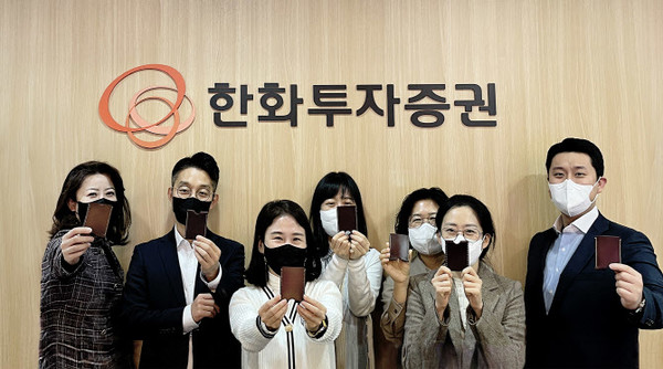 ▲한화투자증권 임직원들이 미혼모 자립 지원을 위해 만든 가죽지갑을 들고 사진촬영을 하고있다.