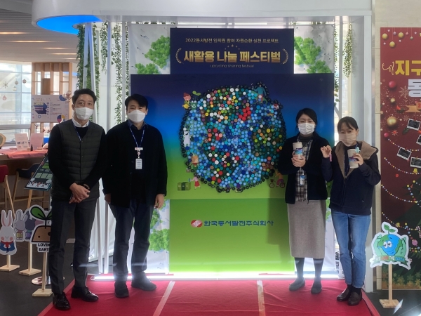 ▲19일 한국동서발전 본사에서 열린 '2022년 새활용 나눔 페스티벌'에서 탄소중립을 주제로 만든 플라스틱 병뚜껑 작품과 함께 동서발전 직원들이 기념사진을 촬영하고 있다.