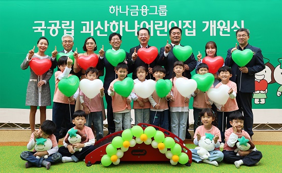 ▲ 개원식에 참석한 강성묵 하나금융그룹 부회장(맨 뒷줄 왼쪽에서 네 번째)이 송인헌 괴산군수(맨 뒷줄 왼쪽에서 다섯 번째)와 어린이집 원장, 학부모, 어린이, 내외빈들과 함께 97번째 어린이집 개원을 축하하며 기념촬영을 하고 있다.