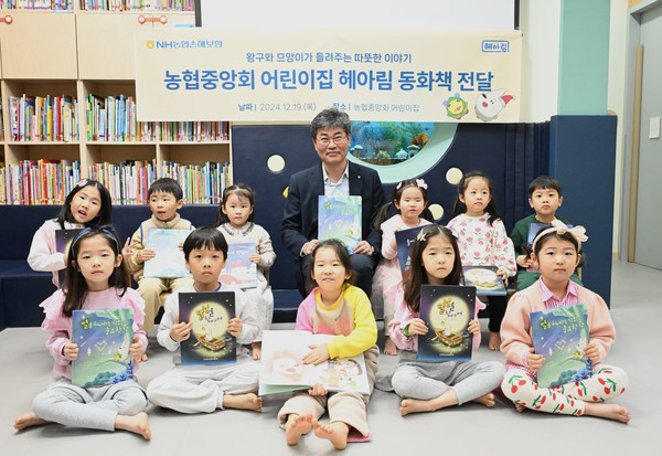 ▲NH농협손해보험 유지영 부사장이 아이들에게 동화책을 전달한 후 기념촬영을 하고 있다