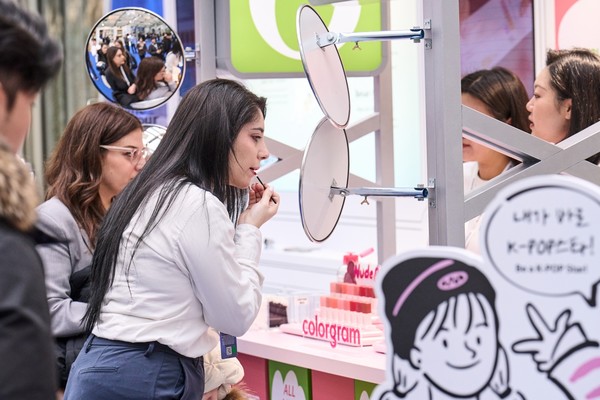▲CJ가 밀라노 코리아하우스 홍보관에 마련한 K뷰티 체험존에서 방문객들이 올리브영 립제품을 직접 발라보고 있다. 사진=CJ